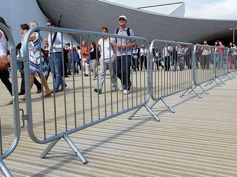 Visitors walk through a pedestrian passageway made up of crowd control barriers.